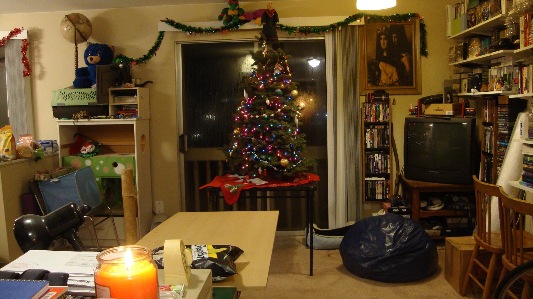 Living room in 2017. Four foot christmas tree on a table in center frame. An old sandbag and CRT television to the right.