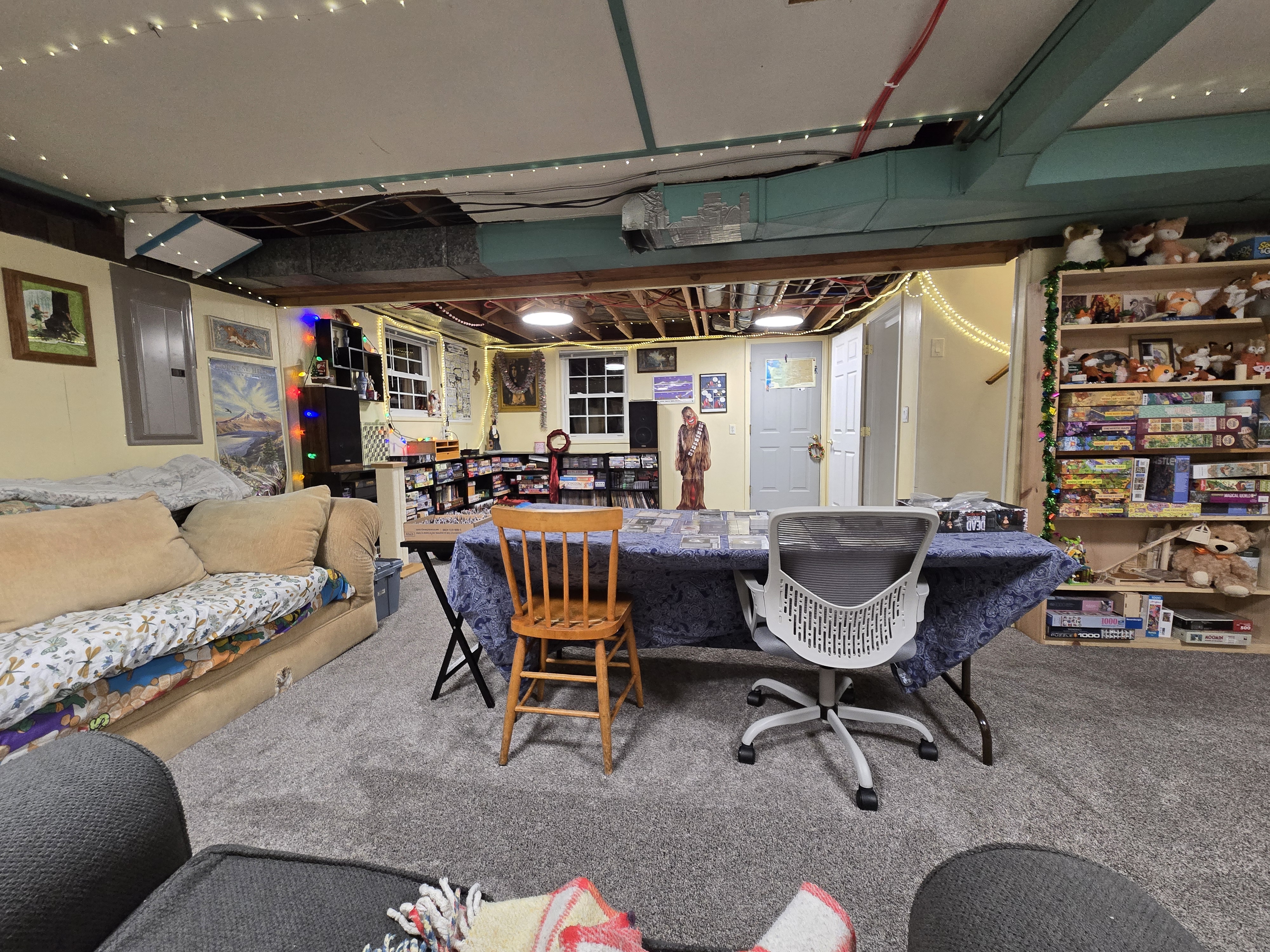 The basement in 2024. A slightly different angle than previous years. This was taken shiortly after I finished removing the last remnants of the ceiling, and putting in nice new LED light fixtures to replace the heavy flickering flourescent ones. We've also got a table out, which we've been playing a lot of board games on.